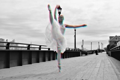 Full length of woman performing ballet dance on bridge against sky