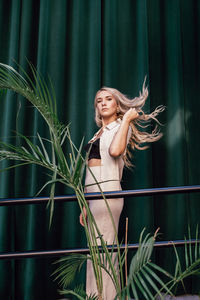 Young woman standing against plants