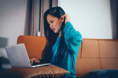 Young woman using mobile phone at home