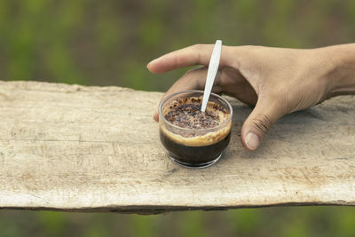 Selective focus cocoa powder in a cup of black coffee in the hand of a man 