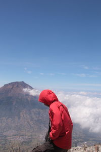 Side view of man standing on mountain against sky