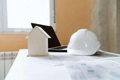 Blueprints, protective helmet, laptop,house model and tools on architect workspace.construction site