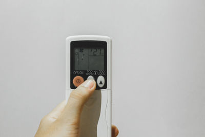 Close-up of hand holding camera against white background