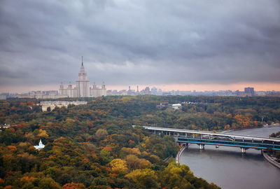 View of trees in city against cloudy sky during sunset