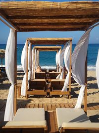 Deck chairs on beach against sky