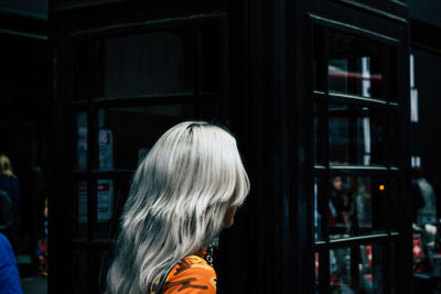 Side view of woman with gray hair standing by building in city