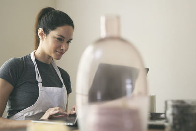 Young woman with ingredients using laptop on table at home