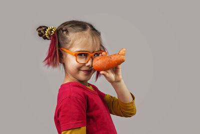 Portrait of woman holding red leaf against white background