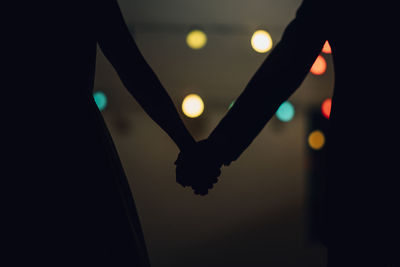 Close-up of silhouette hand holding illuminated light at night