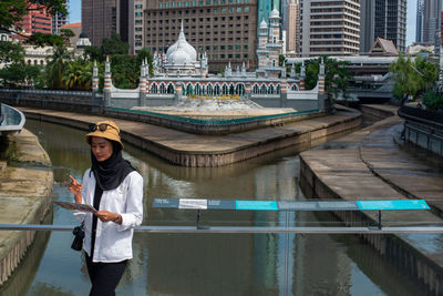 Reflection of man standing on bridge over canal in city