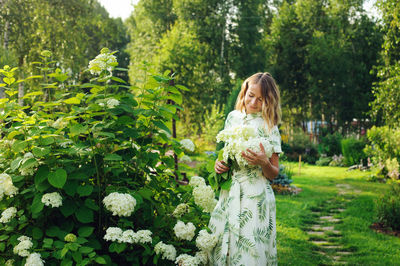 Rear view of woman standing by flowering plants