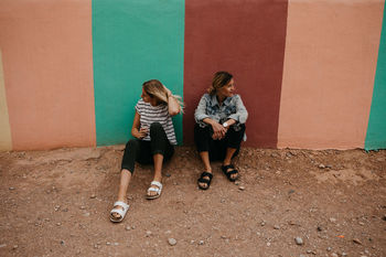 FULL LENGTH OF WOMEN STANDING AGAINST WALL