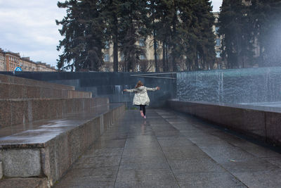 Happy little cute girl having fun in splashes a fountain