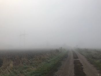 Scenic view of field in foggy weather against sky