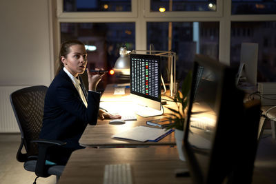 Businesswoman talking on phone while working at office at night