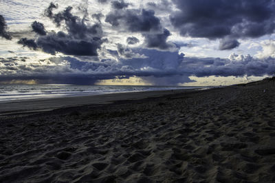 Scenic view of beach against cloudy sky