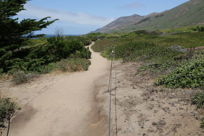 Road leading towards mountains against sky