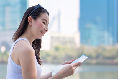 Side view of young woman using mobile phone outdoors