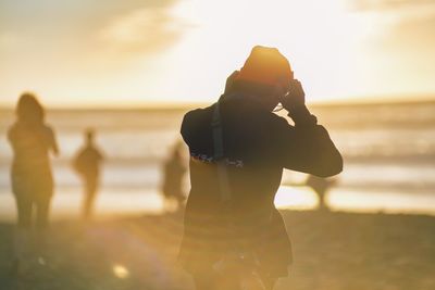 Woman standing on beach at sunset