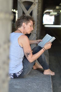 Mature woman reading bible in underpass