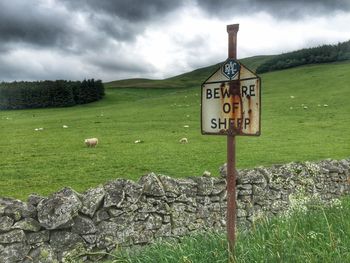 Information sign on field against sky