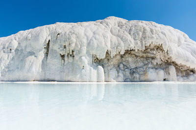 Scenic view of frozen lake against clear blue sky