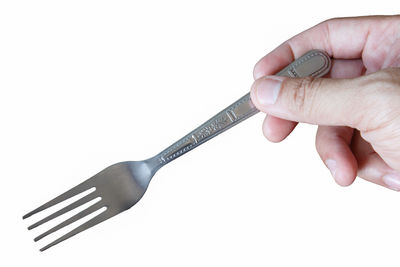 Close-up of hand holding metallic object over white background