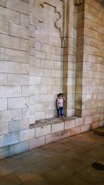 Full length of woman standing against brick wall