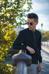 Young man with bicycle against trees
