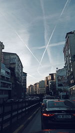 Cars on city street and buildings against sky