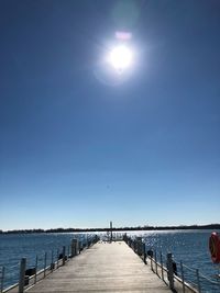 Pier over sea against clear blue sky