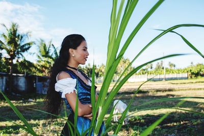 Side view of woman standing on field against sky