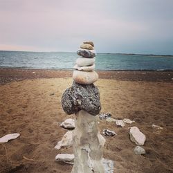 Stack of pebbles on beach against sky