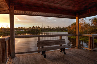 Empty bench against sky during sunset