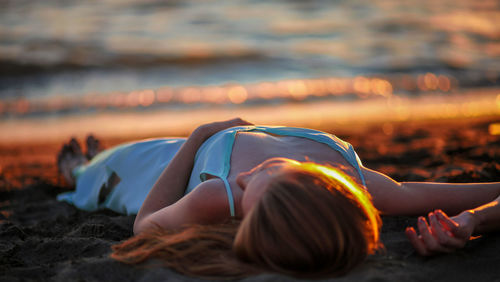 Young woman lying on beach during sunset