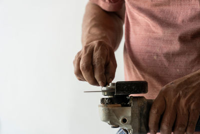 Man using angle grinder, cutting a screw, friction sparks, clamping screw with tweezers concentratio