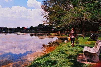People standing by lake against sky