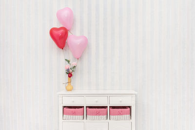 Close-up of heart shape with pink flowers against wall