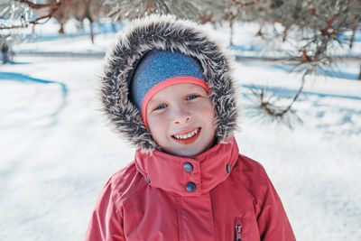 Cute adorable happy caucasian smiling girl in pink jacket with fur hood during cold winter day