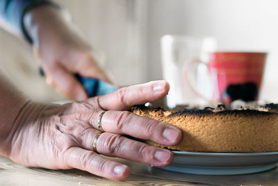 Close-up of hands cutting cake