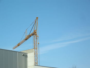 Low angle view of crane against blue sky