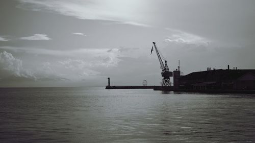 Cranes at commercial dock against sky