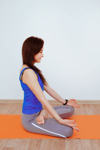 Woman sitting on hardwood floor against wall