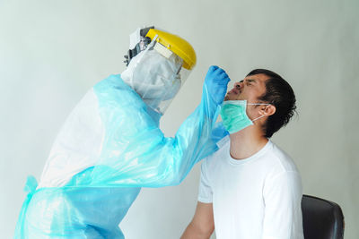 Young woman holding umbrella against wall