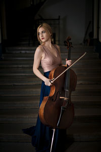 Beautiful woman holding cello while standing on steps