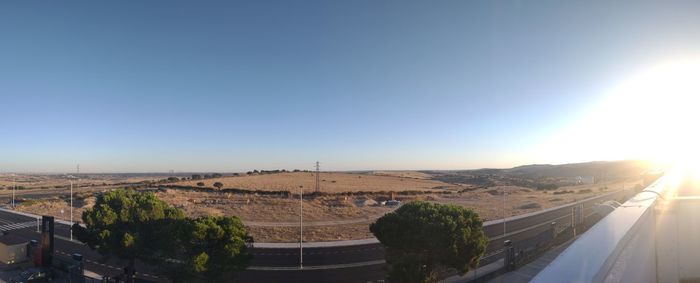 Road leading towards city against clear sky