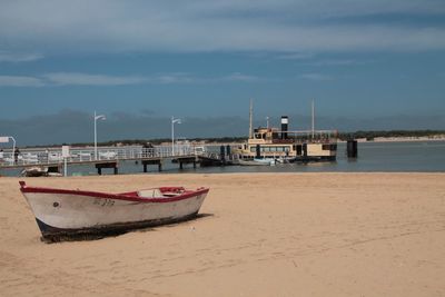 Boat moored on beach against sky