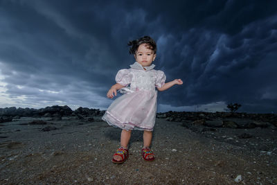 Girl standing on rock against sky