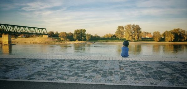 Rear view of boy in water against sky