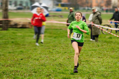 Teenage girl running on grassy field during event